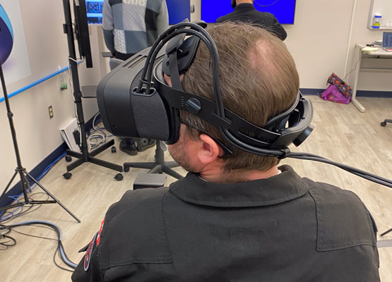 Une personne vêtue d’une combinaison noire utilise un casque de réalité virtuelle.