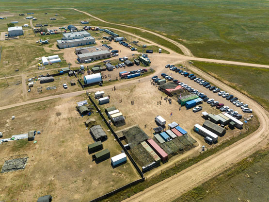 Vue aérienne par drone montrant plusieurs conteneurs maritimes et tentes installés en prévision d’un exercice militaire.
