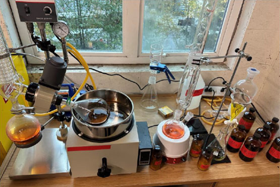 Une table sur laquelle se trouvent du matériel de chimie, quelques récipients en verre et un récipient contenant du liquide.