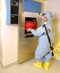 Photo : Un scientifique en combinaison de NC4 décontaminant des déchets