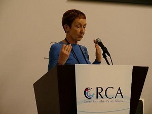 Un conférencier parle et gesticule à une estrade devant laquelle se trouve le logo de l’AROC. 