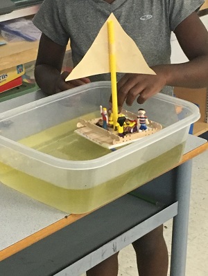 A young student eagerly tests the capacity of her newly constructed boat.