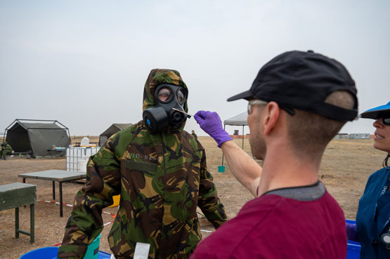 Un soldat en tenue de protection est soumis à un prélèvement d'échantillons