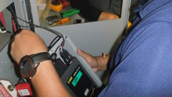A person installs a meter in a grey electrical box.