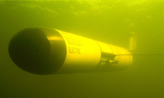 A long cylinder glider with wings in darkness underwater.